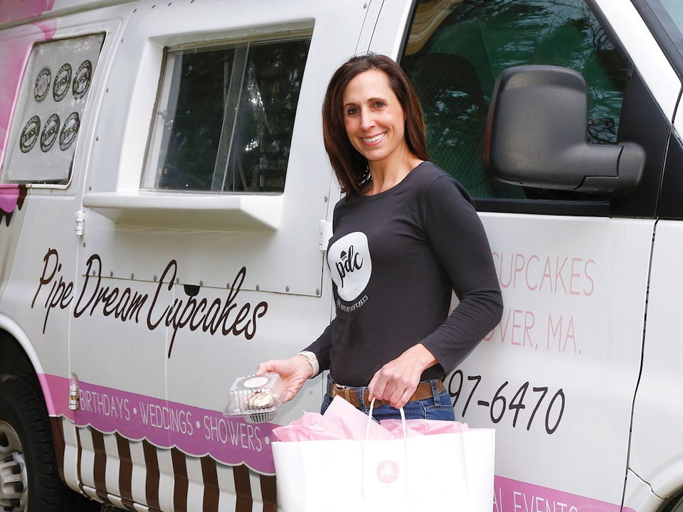 Nadine Levin stands next to her customized Chevy Express van outfitted with pink and black graphics for her Pipe Dream Cupcakes business.