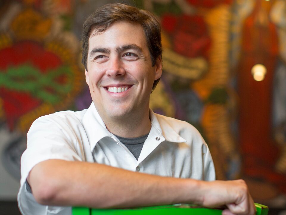 Chef Miles Landrem in front of a colorful wall mural at Landrem’s Mexican restaurant.