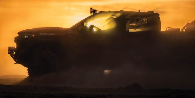 Chad Hall's racing Colorado ZR2 is seen in silhouette against a setting sun.