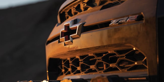 A closeup of the dusty front of Chad Hall's racing Colorado ZR2 and the Chevy bowtie badge.
