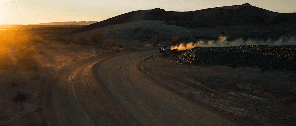 A gif of Chad Hall's racing Colorado ZR2 kicking up dust at sunset as he drives through a remote desert area.