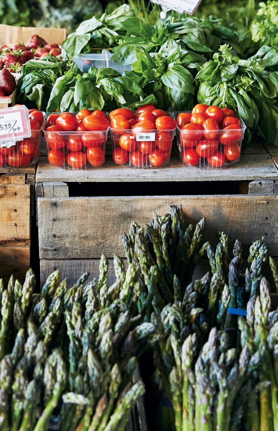 Fresh asparagus and tomatoes on display at a farmers market.