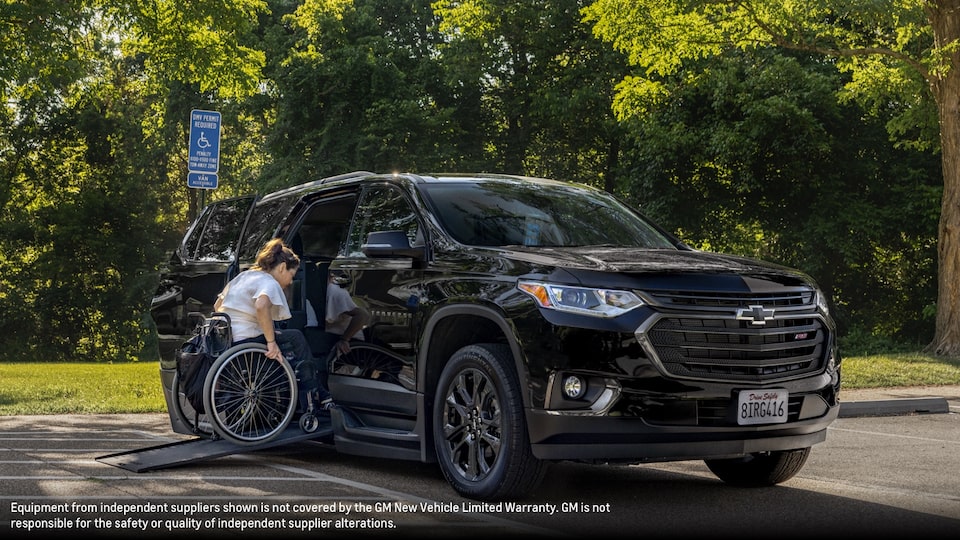 Joanna Bonilla usa una silla de ruedas para subir una rampa y entrar en una Chevy Traverse en Negro.