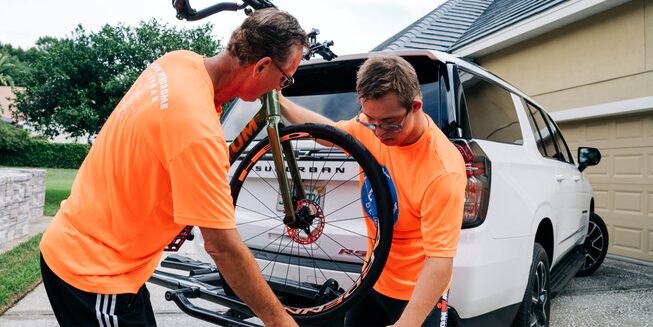 Chris y Nik Nikic cargan su bicicleta en un soporte ubicado en la parte trasera de su Chevy Suburban.