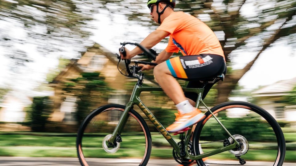 Chris monta su bicicleta por el vecindario mientras entrena para el triatlón Ironman.
