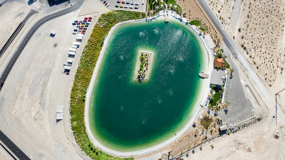 Una fotografía aérea de un lago artificial con una isla rectangular en el centro en un club de campo de automovilismo.