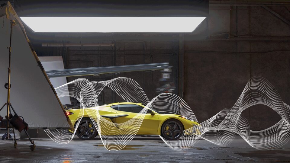 A yellow Corvette Z06 sits in a warehouse type of building in front of a dark background and brightly lit from the front. Illustrated sound waves weave around the car.