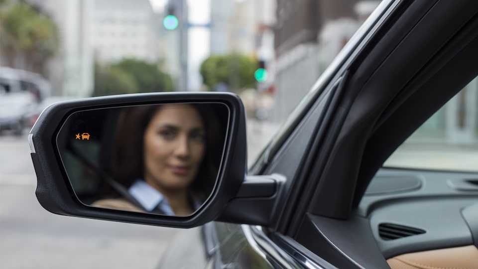 Close-up photo of a woman’s reflection in the driver’s side mirror of an Equinox.