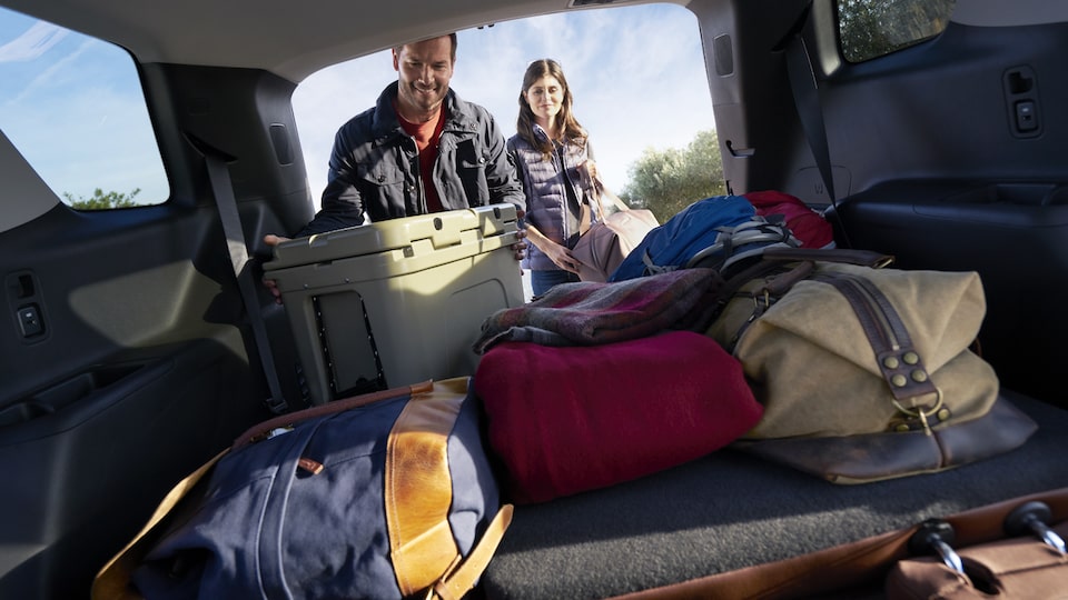A man and woman unloading camping gear from the rear of a Traverse.