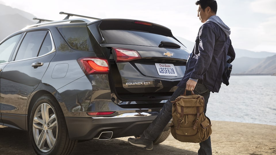 A man holding a bag opens the Equinox hands-free liftgate.