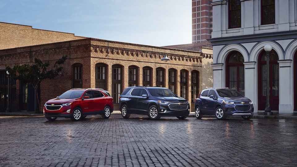 An Equinox, Traverse and Track parked on a city street.