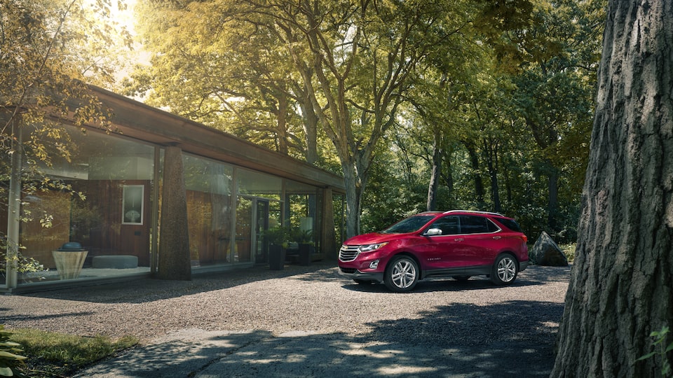 An Equinox parked in front of a house with floor-to-ceiling windows.