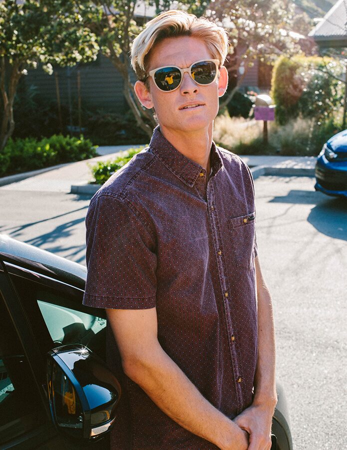 Kevin Schulz, wearing sunglasses, stands in a parking lot next to a Bolt EV.