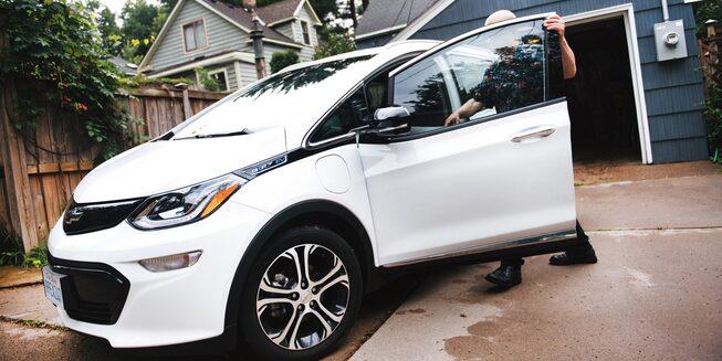 A man enters the driver’s door of a Bolt EV.