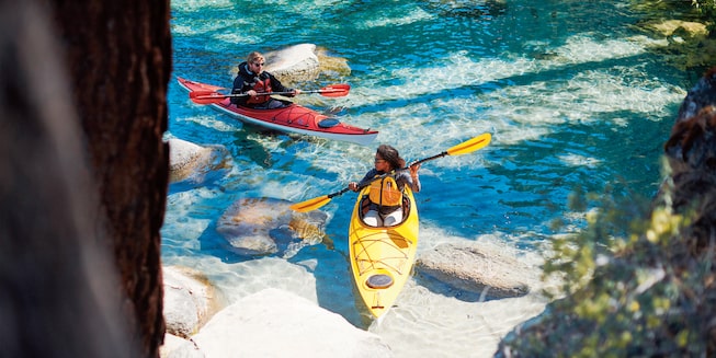 Dos aficionados al kayak reman cerca de la costa del Lago Tahoe.