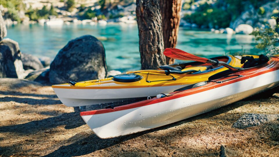 Kayaks rojos y amarillos en el piso cerca de la costa.