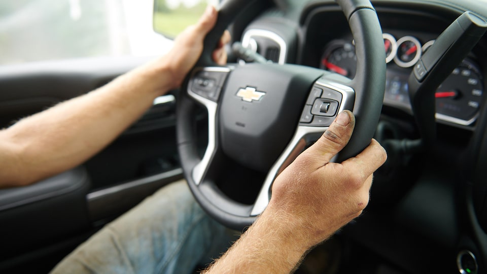 A close-up photograph of a man’s hands holding the 2019 Silverado’s steering wheel.