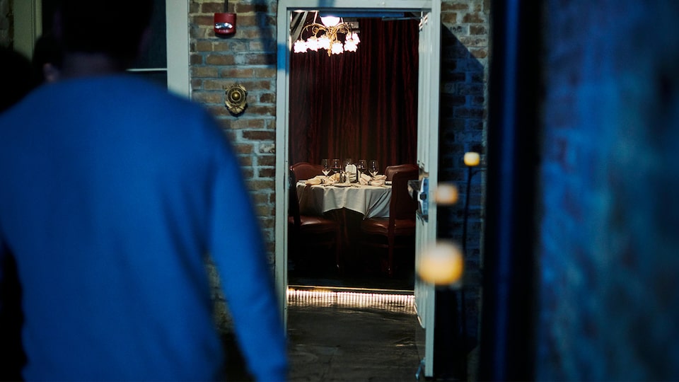 Una mesa puesta con vajilla y cristalería, vista a través de una puerta abierta, sin ocupantes en el restaurante Muriel's Jackson Square en Nueva Orleans.