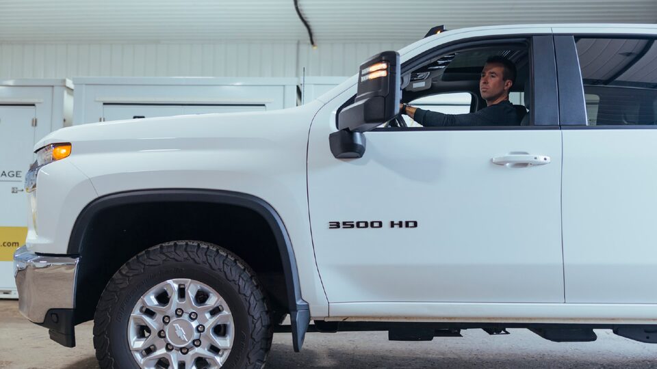 Patrick Carl sits in the driver’s seat of his white Silverado 3500 HD inside his storage warehouse.
