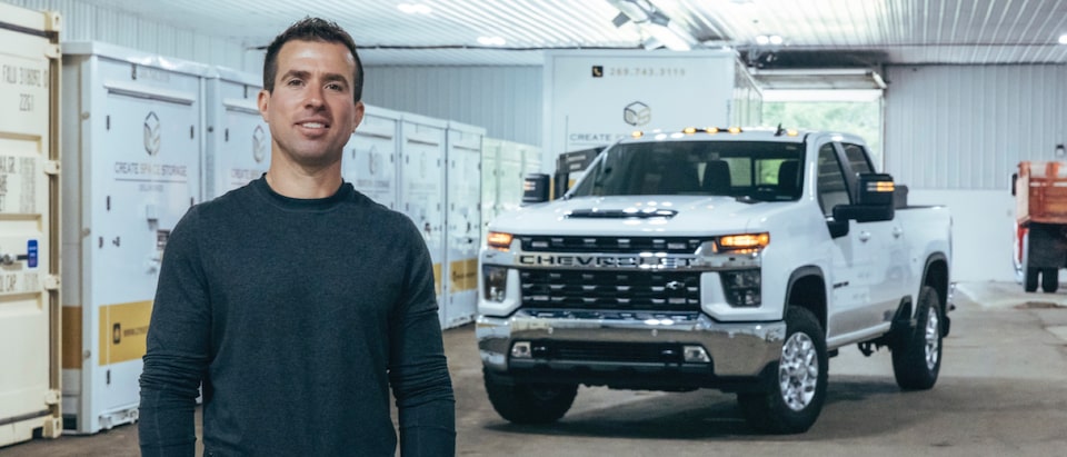 Patrick Carl stands in front of his white Silverado 3500 HD pickup inside his storage warehouse.