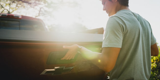A man closes the tailgate of a red Chevrolet Colorado ZR2.