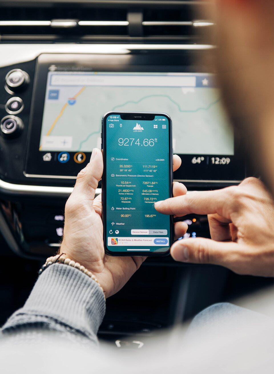 A closeup of someone in the front passenger seat of a Bolt EUV uses an app on their phone.
