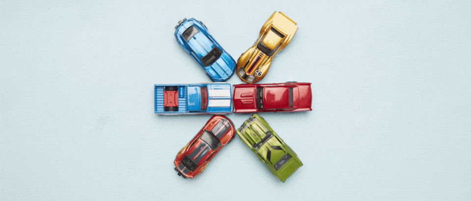 A gif animation of six Hot Wheels cars seen from above as they move out into a circle and then come together in the center.