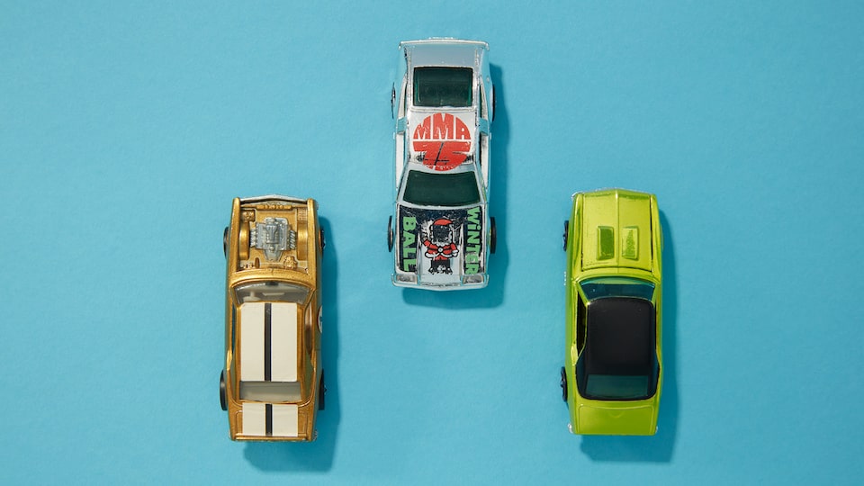Three Hot Wheels cars seen from above on a blue background.