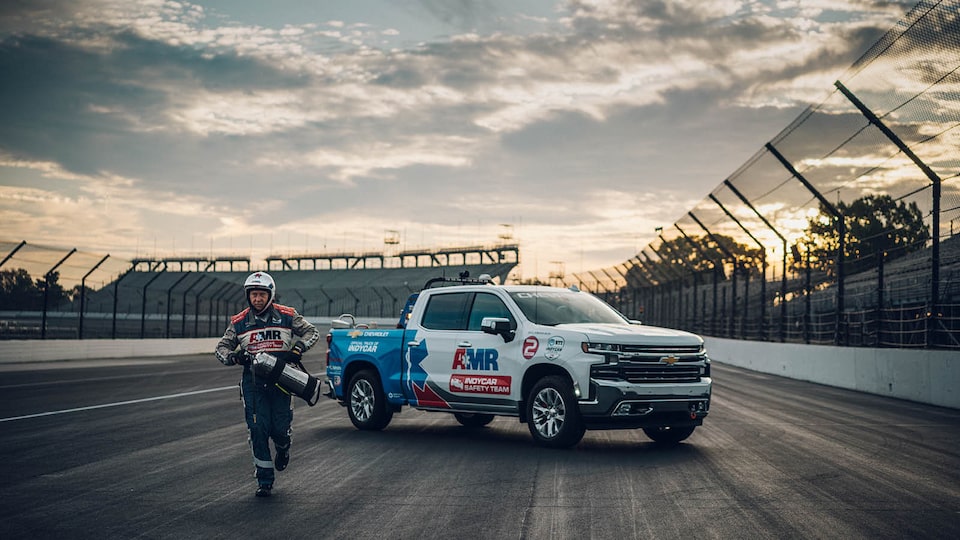 TIm Baughman carries a fire extinguisher as he runs away from a Chevrolet Silverado parked on the race track.
