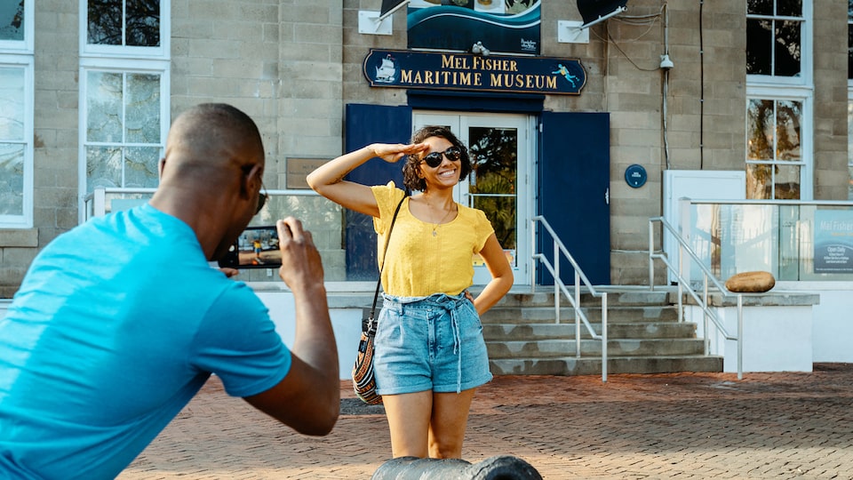 Un hombre le toma una foto a una mujer frente al Museo Marítimo Mel Fisher.