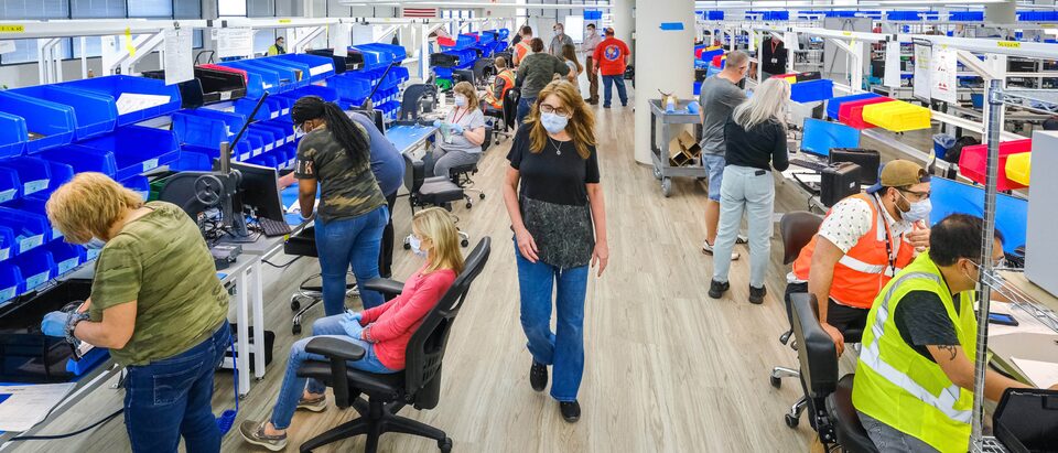 Una toma interior de la planta de GM en Kokomo reacondicionada para fabricar respiradores mecánicos, con filas de estaciones de trabajo distanciadas y equipos.