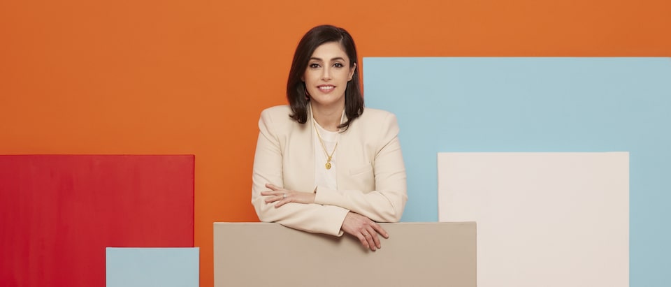 Jennifer Widrick stands in front of a wall with blocks of colors in orange, red, blue, white, and brown.