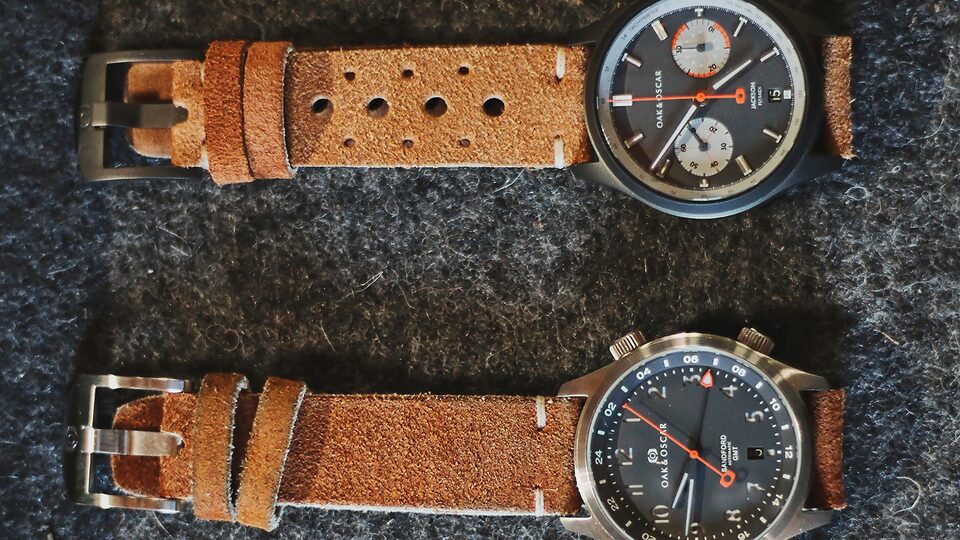 Dos relojes con correas de cuero marrones sobre una mesa.