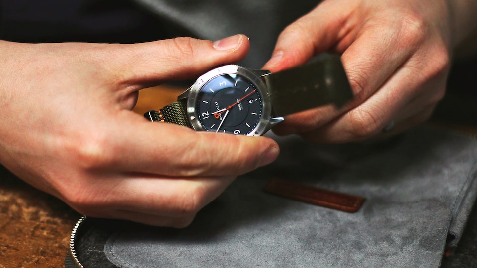 Primer plano de manos sosteniendo un reloj.