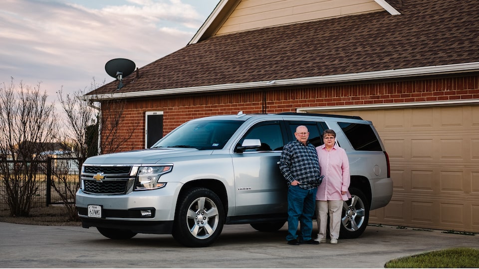 OnStar Members David and Cheryl Roberts stand next to their silver Chevy Tahoe in their driveway.