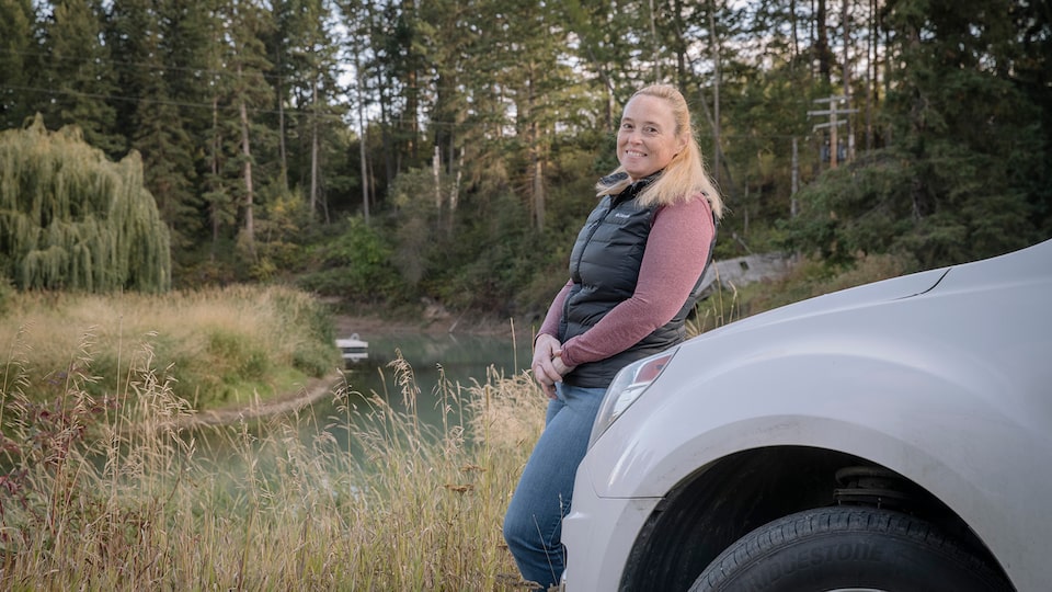 OnStar Member Jennifer Allen leans on the front of her truck with a field and trees in the background.