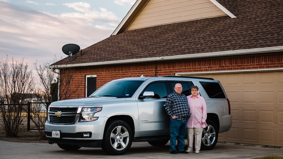 OnStar Members David and Cheryl Roberts stand next to their silver Chevy Tahoe in their driveway.