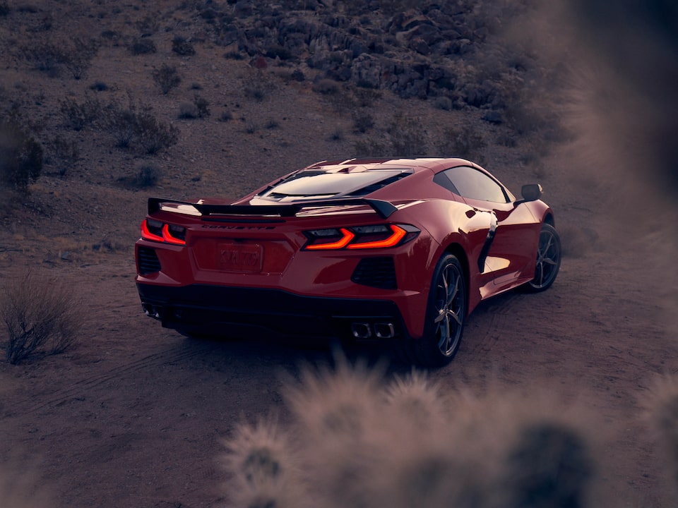 Un coupe Corvette 2020 en Rojo Antorcha en un paisaje desértico, visto desde atrás con las luces de freno encendidas.
