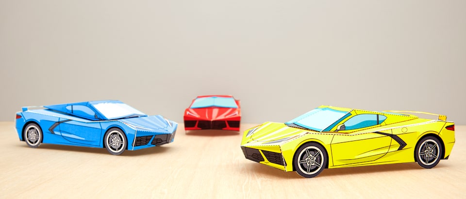 Tres modelos armados en papel del Corvette 2020 en rojo, amarillo y azul.