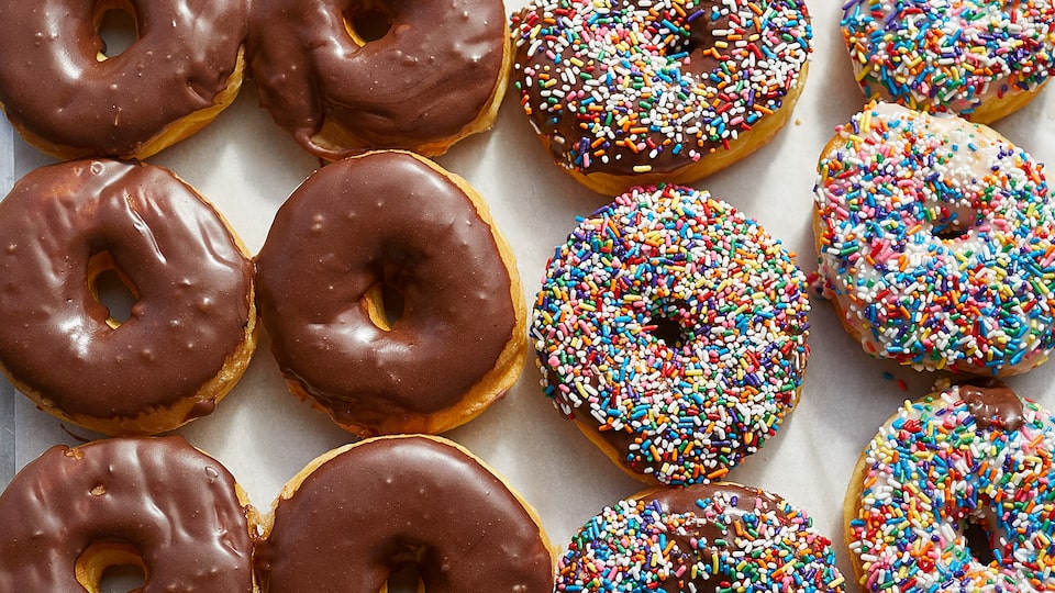 A tray of chocolate-glazed and sprinkle-covered donuts.