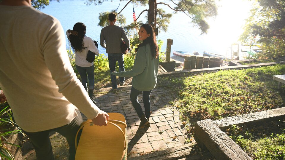 A group of women walk down wooden steps outside toward a lake below them.