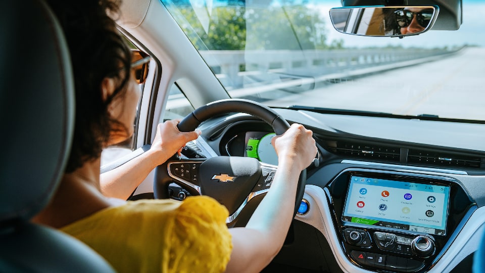 A shot from the rear seat of a Bolt EV of a woman in the driver’s seat.