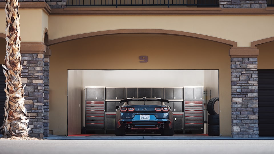 The rear end of a Camaro parked inside a well-equipped garage workshop at a motorsports country club.