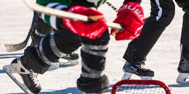 A close-up of someone in full hockey gear holding a stick as they skate across the ice.