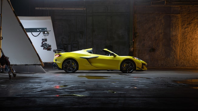 A yellow Corvette Z06 with Z07 Performance Package sits in the warehouse location used for the photo shoot, with background sheeting and lighting suspended behind it.