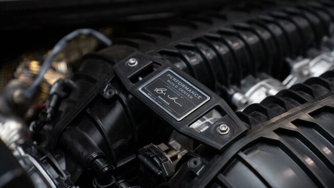 A close-up shot of the small plaque on a Corvette Z06 engine engraved with the name of the person who hand-assembled the engine.