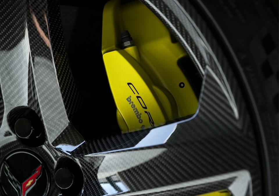 Close-up shot of wheel of a Corvette Z06, with the color-coordinated yellow Brembo brake pads showing through the spokes.