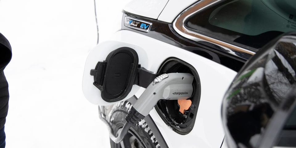 Un cable de carga enchufado en un lado de un Bolt EV Blanco.