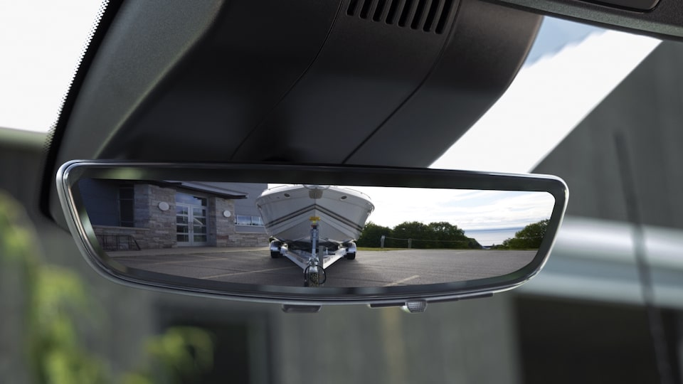 Primer plano del espejo retrovisor de una Silverado HD que muestra cómo puede configurarse para expandir el área detrás y alrededor de la camioneta al acarrear un remolque.