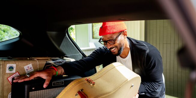 Redray Frazier, wearing a bright red hat, loads equipment into the back of a Blazer.